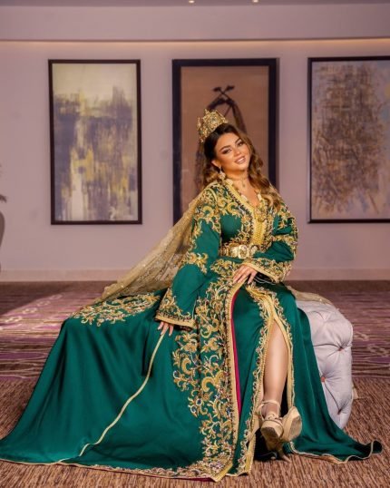 CAFTAN EXPORT Découvrez l'élégance intemporelle du caftan henna, une pièce traditionnelle marocaine magnifiquement ornée. Nos caftans en henna allient beauté et tradition pour des moments inoubliables. Explorez notre collection unique aujourd'hui ! Le caftan, composé de deux pièces en velours de soie vert royal, est travaillé avec broderie, sfifa et des boutons en skali doré. La partie inférieure est un caftan sans manche, confectionnée en drap de soie vert royal est également perlé à la main. Il est accompagné d'une ceinture assortie en métal.