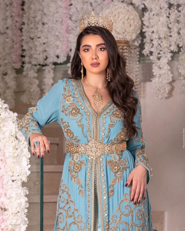 CAFTAN EXPORT Découvrez l'élégance intemporelle du caftan henna, une pièce traditionnelle marocaine magnifiquement ornée. Nos caftans en henna allient beauté et tradition pour des moments inoubliables. Explorez notre collection unique aujourd'hui ! Le caftan Sabrine, composé de deux pièces en crêpe de soie vert royal, est orné de broderies, de sfifa et de boutons en skali bronze entièrement perlés à la main. La partie inférieure est un caftan sans manches, confectionné en drap de soie vert royal. Il est accompagné d'une ceinture assortie en métal.