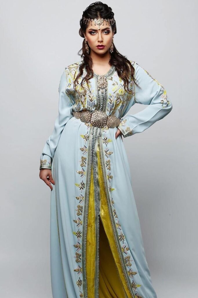 CAFTAN EXPORT Découvrez l'élégance intemporelle du caftan henna, une pièce traditionnelle marocaine magnifiquement ornée. Nos caftans en henna allient beauté et tradition pour des moments inoubliables. Explorez notre collection unique aujourd'hui ! Le caftan Siham, composé de deux pièces en draps de soie vert, travaillé en zewak maalam, sfifa et button en skali doré. Le bas est confectionné en lamé doré pailletée, Il est accompagné d'une ceinture assortie en métal.