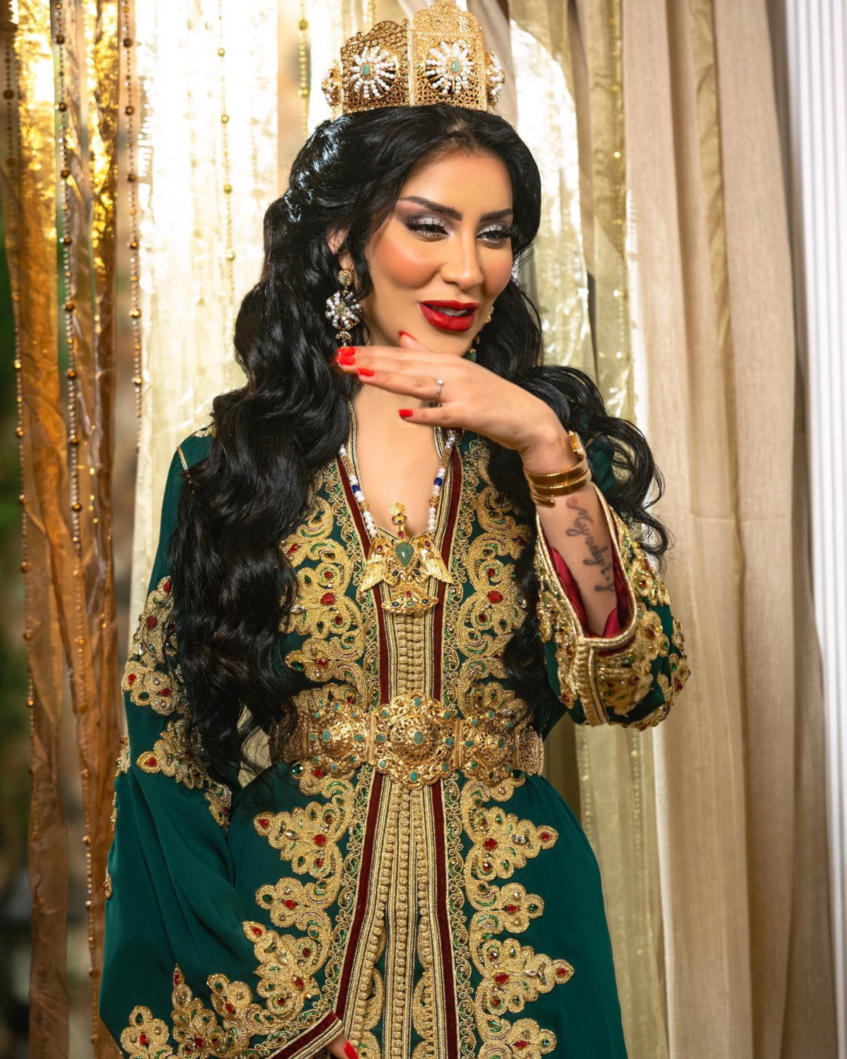 Caftan Market Place Découvrez l'élégance intemporelle du caftan henna, une pièce traditionnelle marocaine magnifiquement ornée. Nos caftans en henna allient beauté et tradition pour des moments inoubliables. Explorez notre collection unique aujourd'hui ! Le caftan se compose de deux pièces en crêpe de soie vert, ornées de broderies dorées, de perles en cristal, de sfifa et de boutons en skali doré. La partie inférieure est confectionnée en drap de soie vert, perlé à la main. Il est accompagné d'une ceinture assortie en métal.