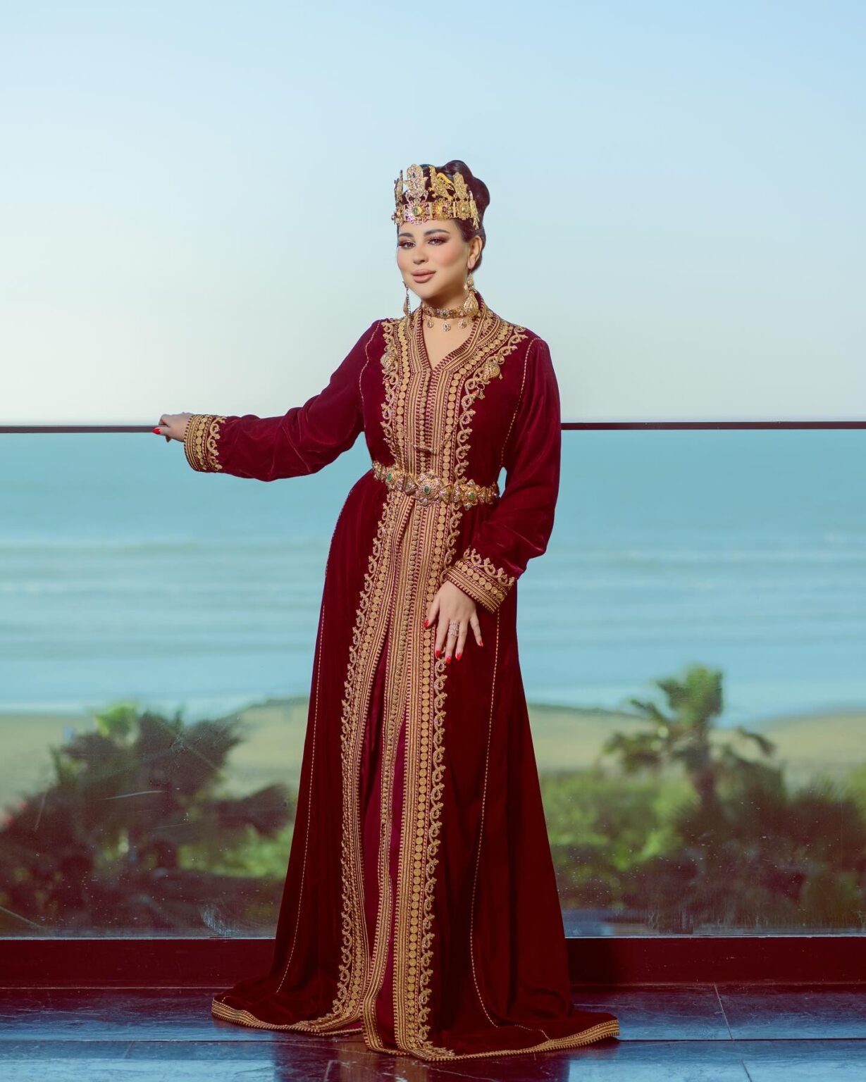 CAFTAN EXPORT Découvrez l'élégance intemporelle du caftan henna, une pièce traditionnelle marocaine magnifiquement ornée. Nos caftans en henna allient beauté et tradition pour des moments inoubliables. Explorez notre collection unique aujourd'hui ! Le caftan Narjiss se compose de deux pièces en velours Bordeau, ornées de broderies dorées, de perles en cristal, de sfifa et de boutons en skali doré. La partie inférieure est confectionnée en drap de soie Bordeau, perlé à la main. Il est accompagné d'une ceinture assortie en métal.