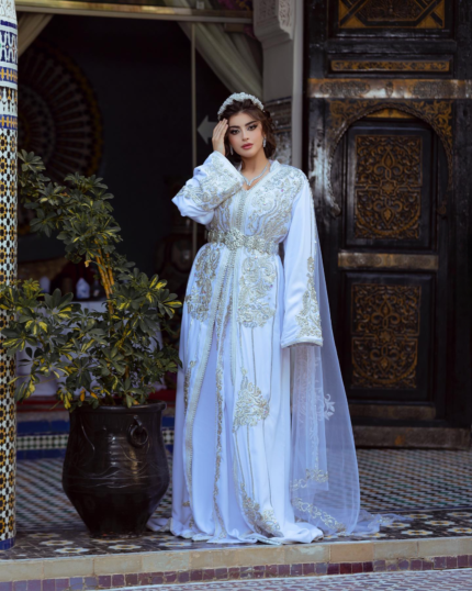 CAFTAN EXPORT Découvrez l'élégance intemporelle du caftan henna, une pièce traditionnelle marocaine magnifiquement ornée. Nos caftans en henna allient beauté et tradition pour des moments inoubliables. Explorez notre collection unique aujourd'hui ! Takchita marocaine haut couture composé de deux pièces. La première pièce est confectionnée en crêpe de soie brodée de fils dorés et rouge, agrémentée de pierres précieuses dorées et rouge de qualité exceptionnelle qui scintillent sous la lumière. La partie inférieure du caftan est réalisée en tissu draps de soie. Elle est accompagnée d'une ceinture en métal doré.